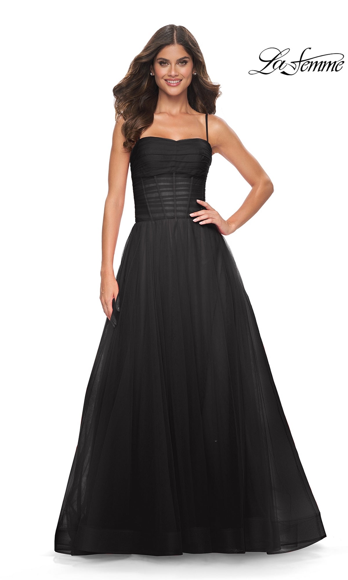 A woman stands against a white background wearing the La Femme Sheer-Waist Long Prom Ball Gown 32017, a black sleeveless dress with spaghetti straps, fitted bodice, full tulle skirt, and an elegant silhouette.